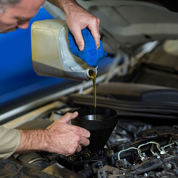 Mechanic pouring transmission fluid into a vehicle transmission system